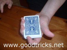 Deck is held pointing towards spectator. Thumb on oneside, first finger at top of deck.