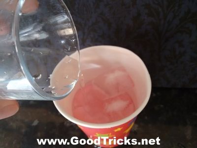 Sponge and ice cubes are already inside cup as water is poured into the cup.