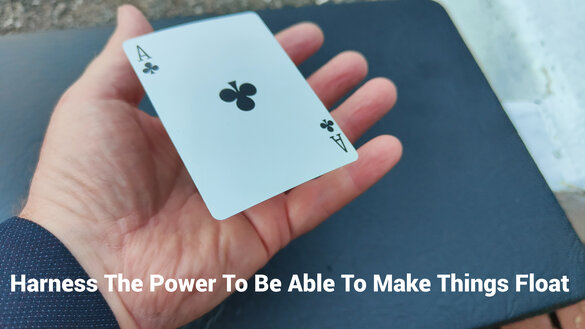 Playing card is made to float above the magician's hand.